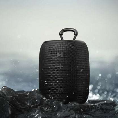 Black portable speaker with water-resistant features on a wet surface